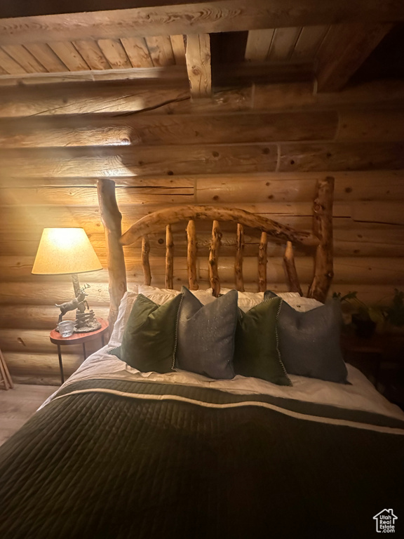 Bedroom featuring log walls, wood ceiling, and beam ceiling