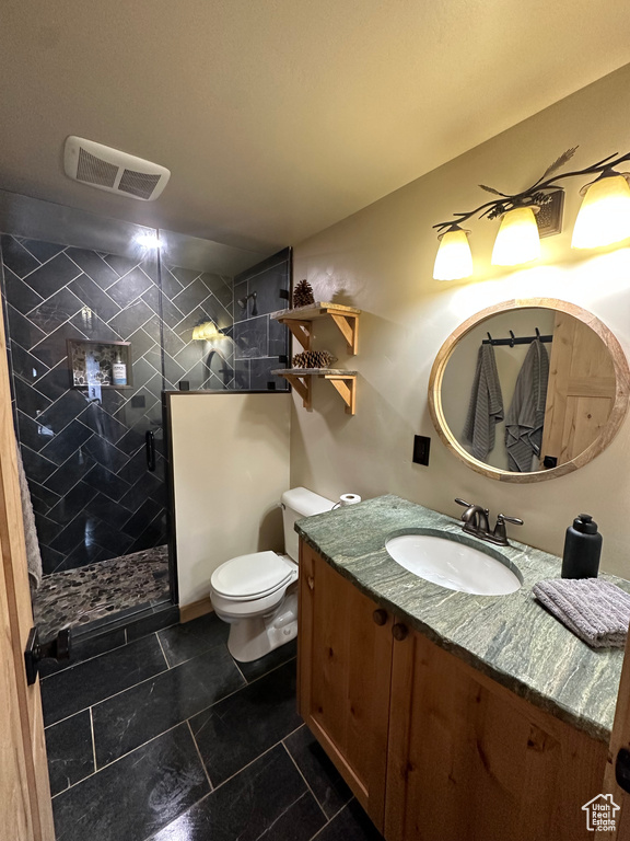 Bathroom featuring a tile shower, tile floors, toilet, and vanity