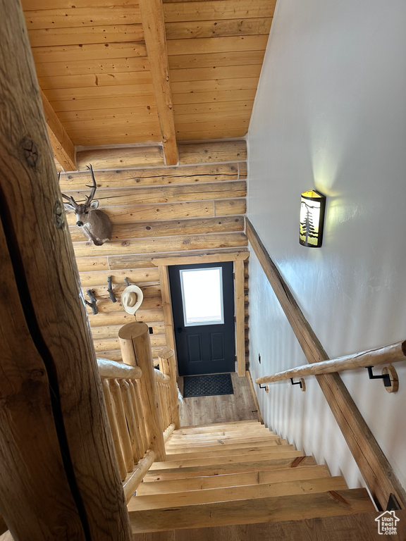 Stairs featuring log walls, light hardwood / wood-style flooring, and wood ceiling