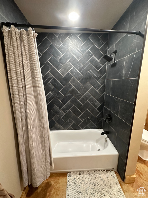 Bathroom featuring toilet, shower / bath combo, and tile floors