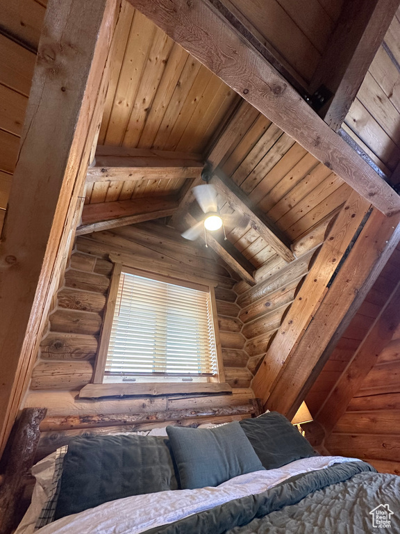 Bedroom featuring lofted ceiling with beams, log walls, and wooden ceiling