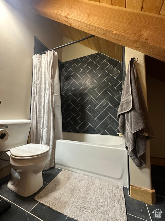 Bathroom featuring toilet, shower / bathtub combination with curtain, and tile floors