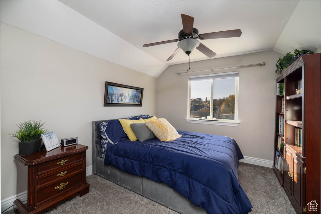 Bedroom featuring vaulted ceiling, dark colored carpet, and ceiling fan