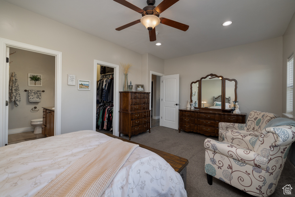 Bedroom with a spacious closet, connected bathroom, a closet, dark carpet, and ceiling fan