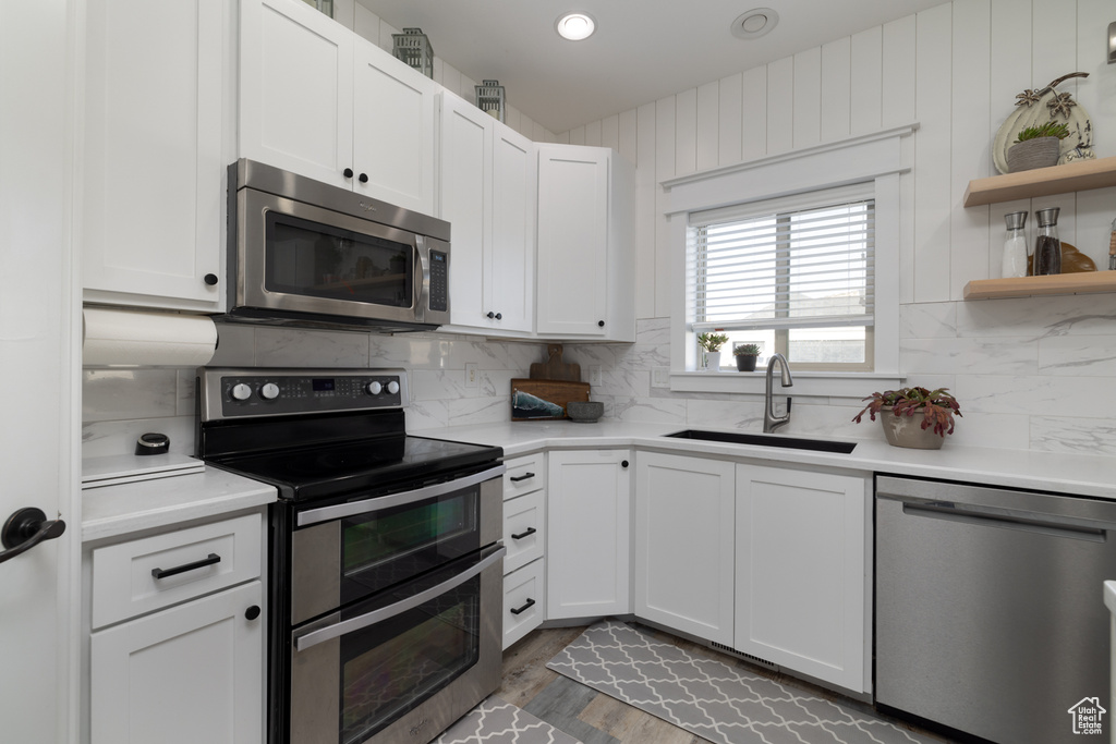 Kitchen featuring backsplash, white cabinets, stainless steel appliances, sink, and dark hardwood / wood-style flooring