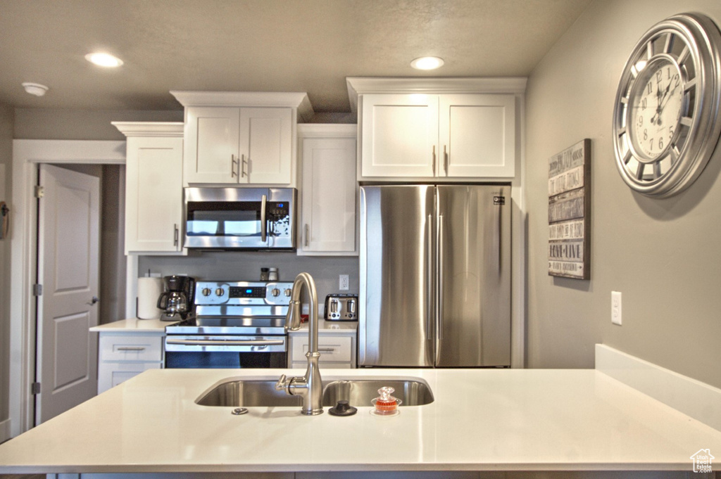 Kitchen with appliances with stainless steel finishes, white cabinets, and sink