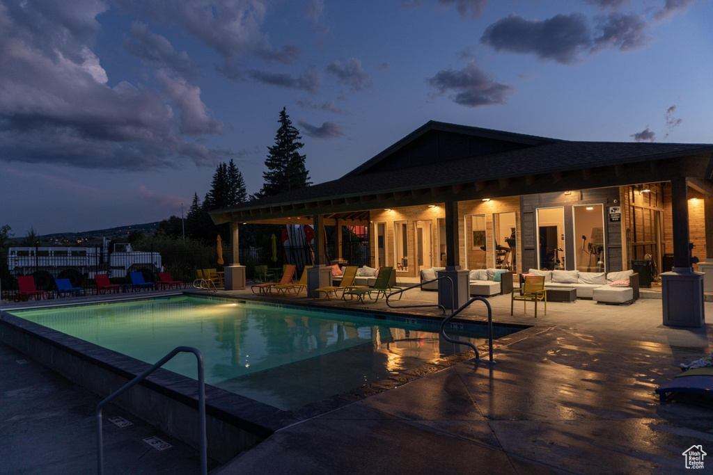 Pool at dusk with a patio and outdoor lounge area
