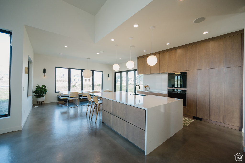 Kitchen featuring a center island with sink, pendant lighting, sink, and double oven