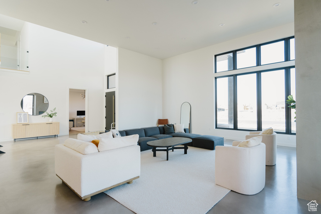 Living room featuring plenty of natural light, concrete flooring, and a high ceiling