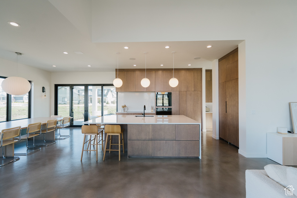 Kitchen featuring sink, pendant lighting, a wealth of natural light, and a kitchen island with sink