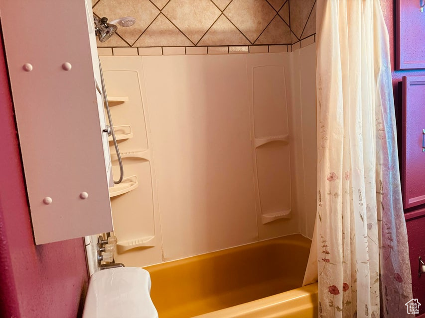 Bathroom featuring toilet and shower / bath combination with curtain
