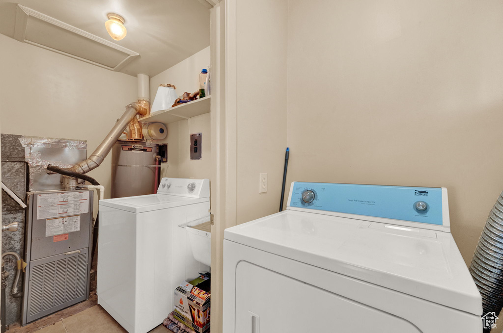 Laundry room with light tile floors, gas water heater, and washing machine and clothes dryer