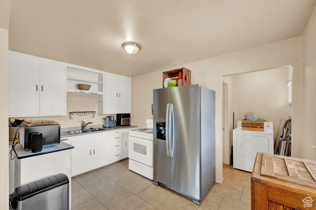 Kitchen featuring light tile floors, sink, white range with gas stovetop, washer / clothes dryer, and stainless steel refrigerator with ice dispenser