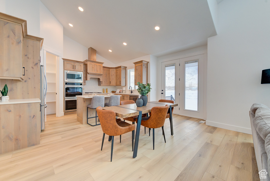 Dining space featuring light hardwood / wood-style flooring, sink, and high vaulted ceiling