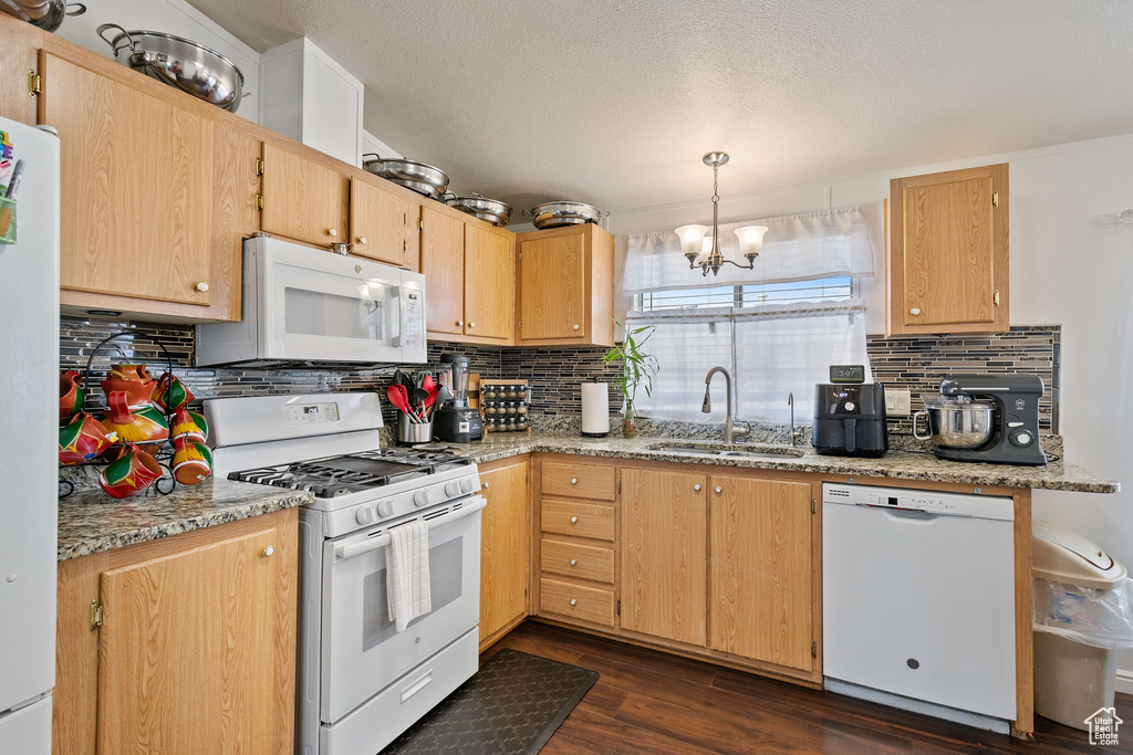Kitchen with dark hardwood / wood-style floors, sink, a chandelier, white appliances, and tasteful backsplash