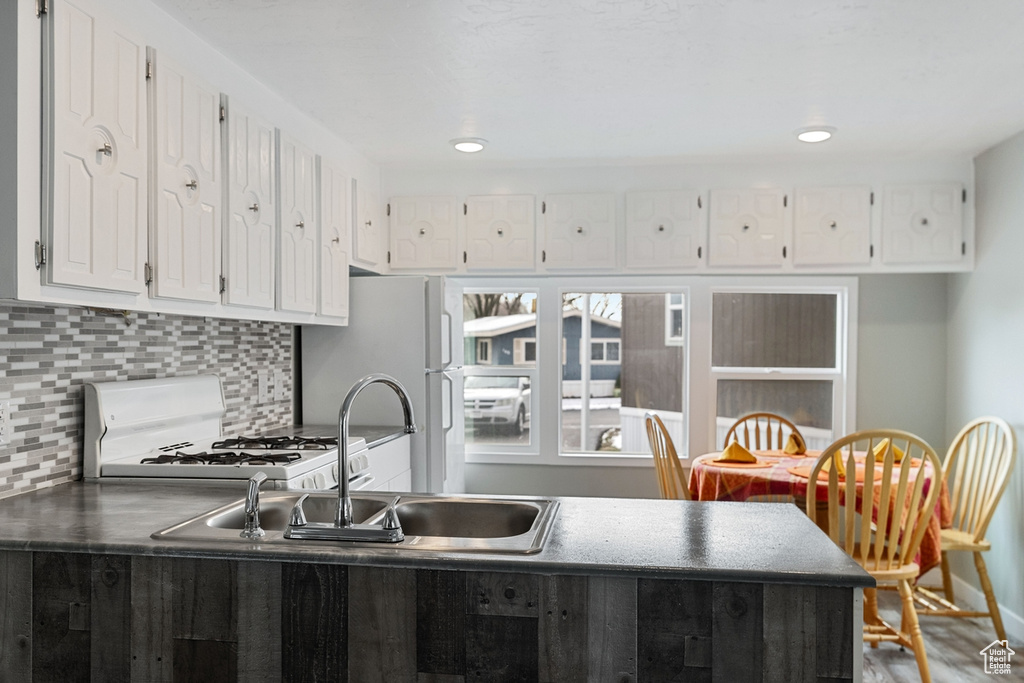 Kitchen featuring white cabinetry, white appliances, sink, and backsplash