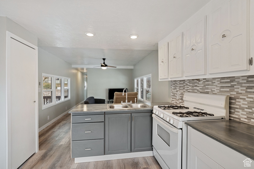 Kitchen with gas range gas stove, gray cabinets, tasteful backsplash, light hardwood / wood-style floors, and ceiling fan