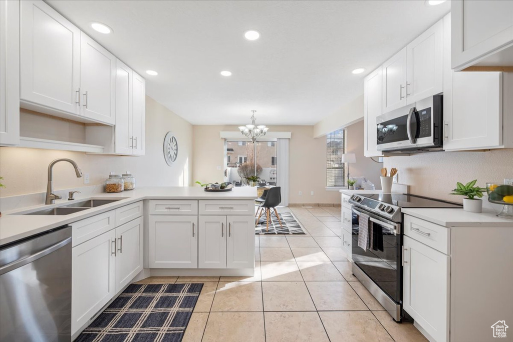 Kitchen with a notable chandelier, sink, light tile floors, white cabinets, and stainless steel appliances