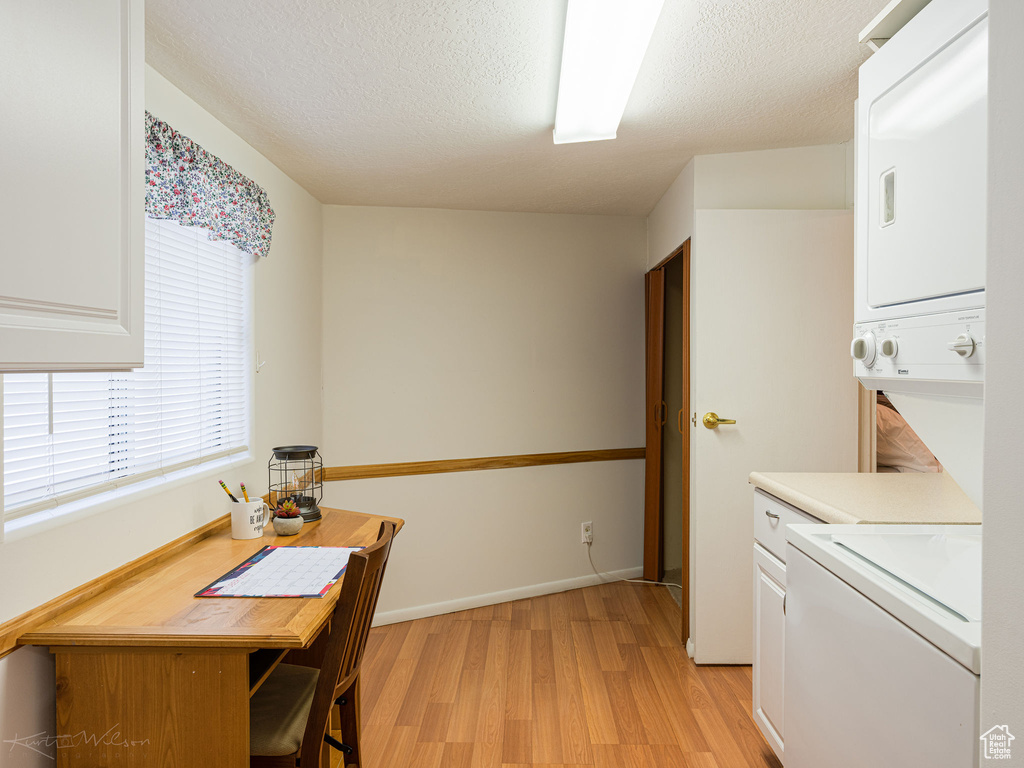 Interior space featuring a textured ceiling, light hardwood / wood-style floors, and stacked washer and clothes dryer