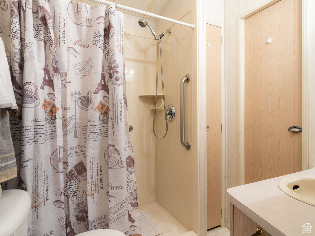 Bathroom with toilet, tile flooring, and curtained shower