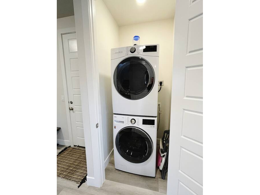Laundry area with stacked washer and dryer and light hardwood / wood-style floors