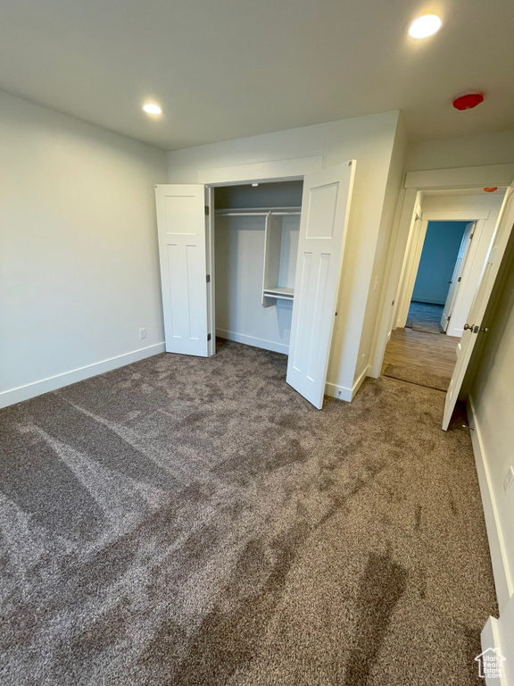 Unfurnished bedroom featuring a closet and dark carpet