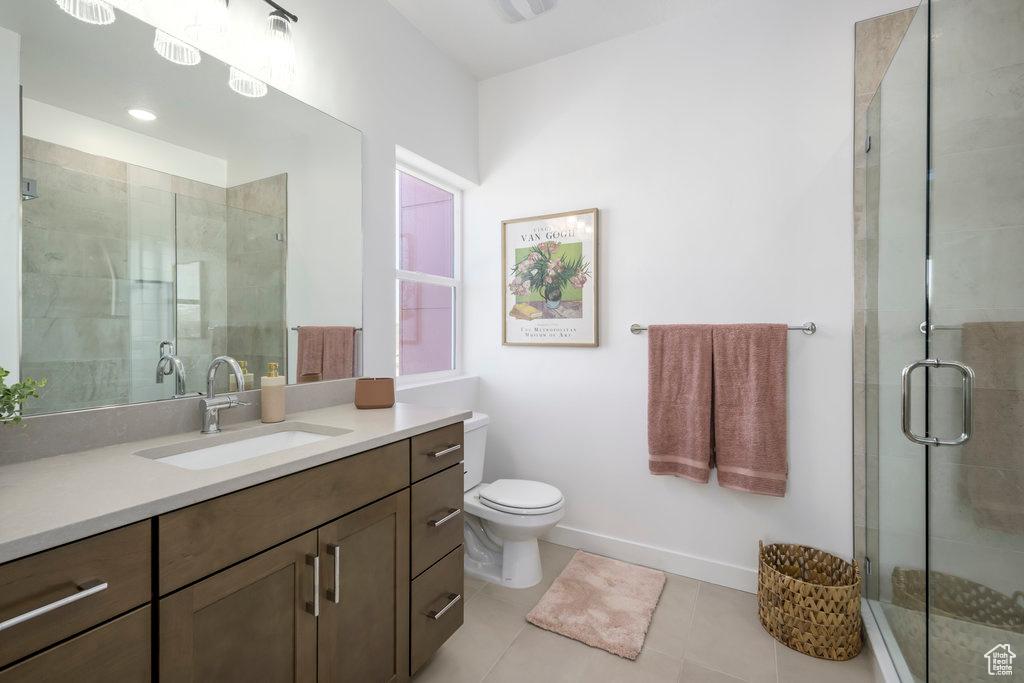 Bathroom featuring tile flooring, walk in shower, vanity, and toilet