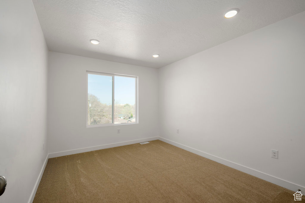 Spare room featuring a textured ceiling and light colored carpet