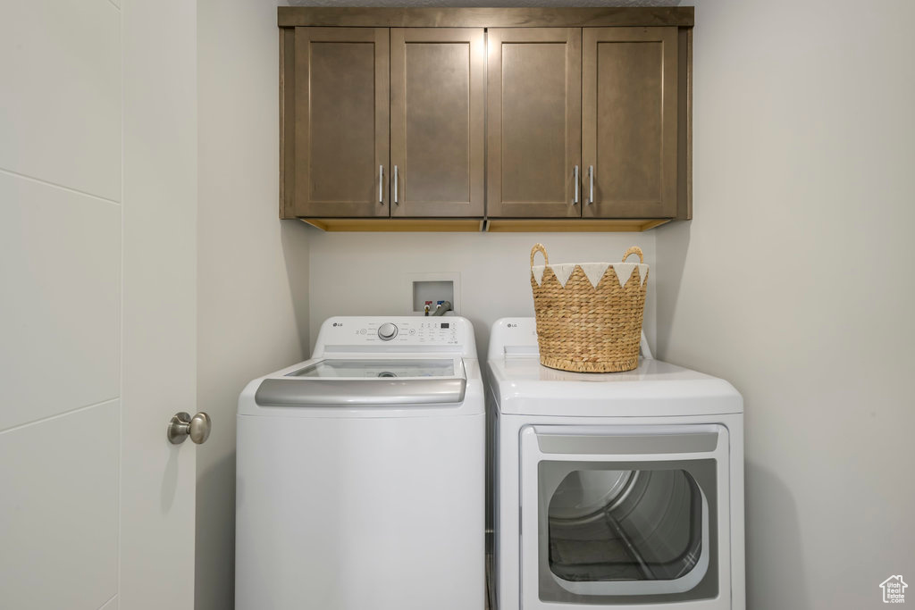 Laundry area featuring separate washer and dryer, cabinets, and washer hookup