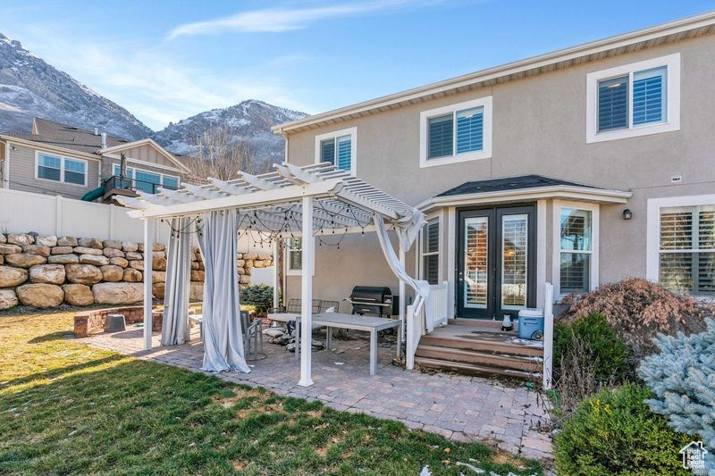Rear view of property featuring a pergola, a mountain view, a lawn, and a patio