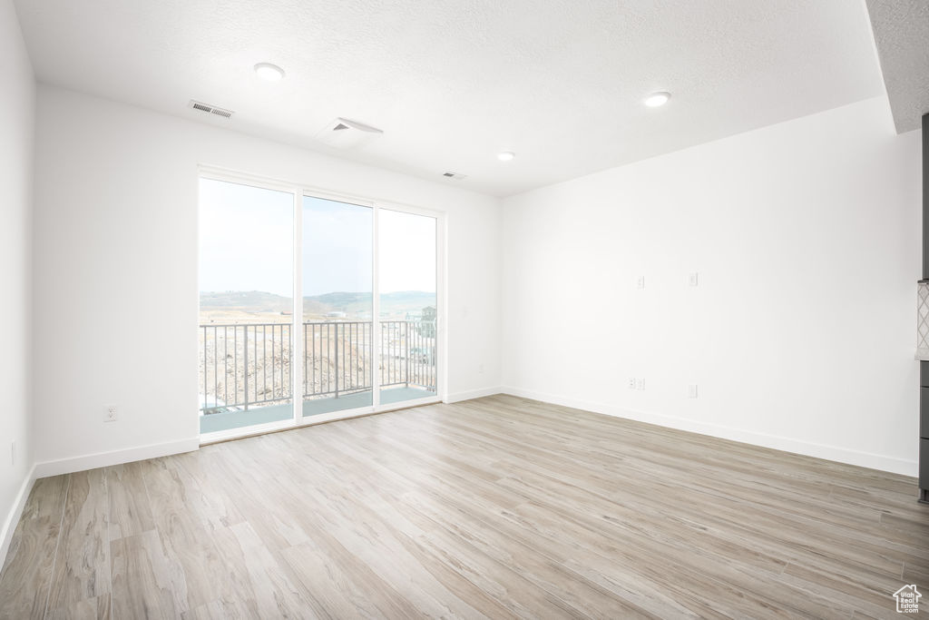 Empty room featuring a mountain view and light hardwood / wood-style flooring
