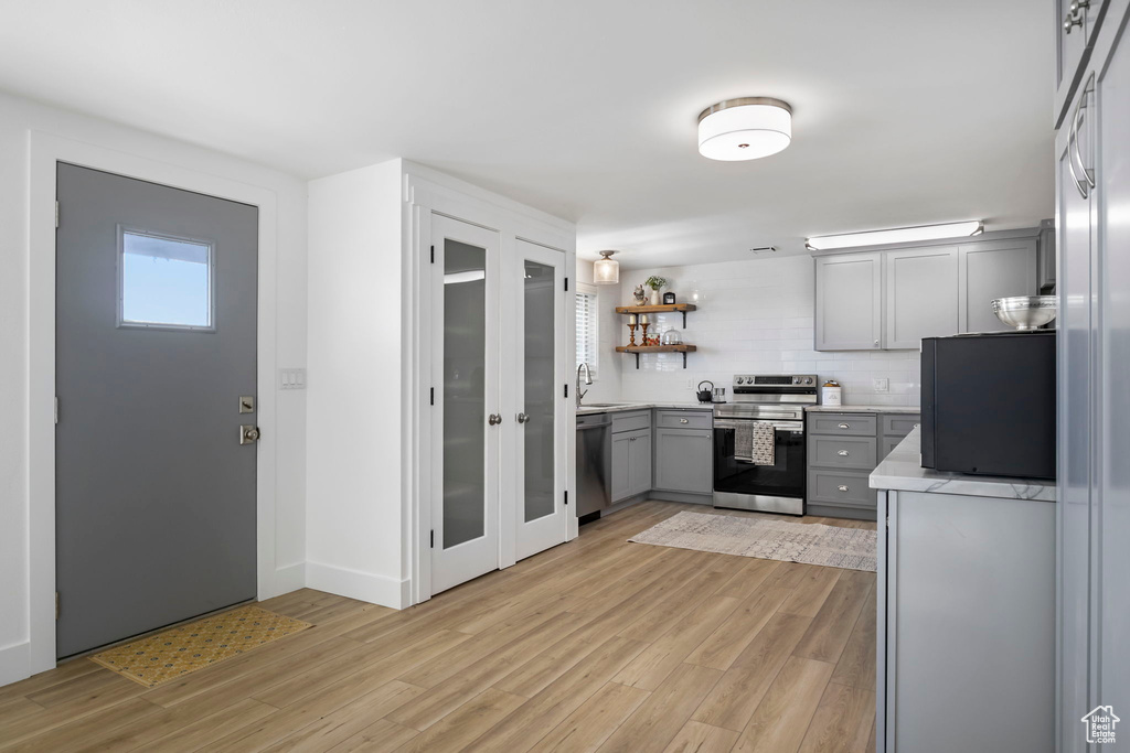 Kitchen with backsplash, light hardwood / wood-style flooring, gray cabinets, and electric stove