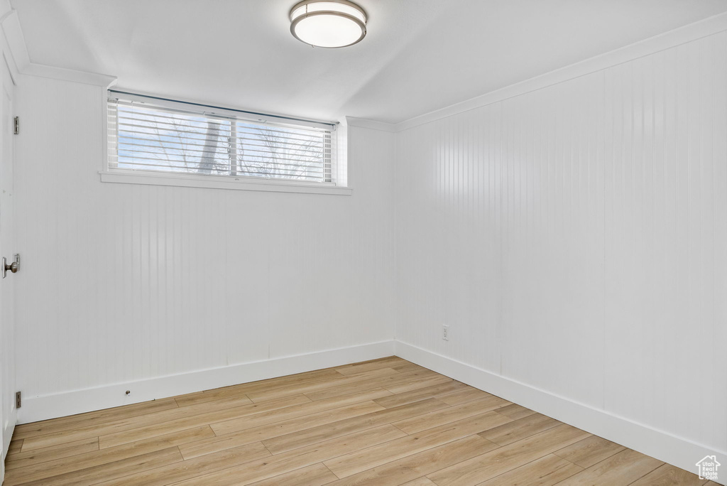 Empty room with ornamental molding and light hardwood / wood-style floors