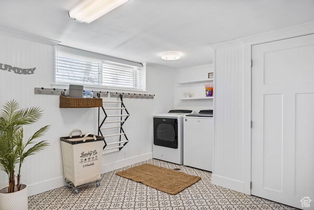 Laundry room featuring light tile flooring, ornamental molding, and independent washer and dryer