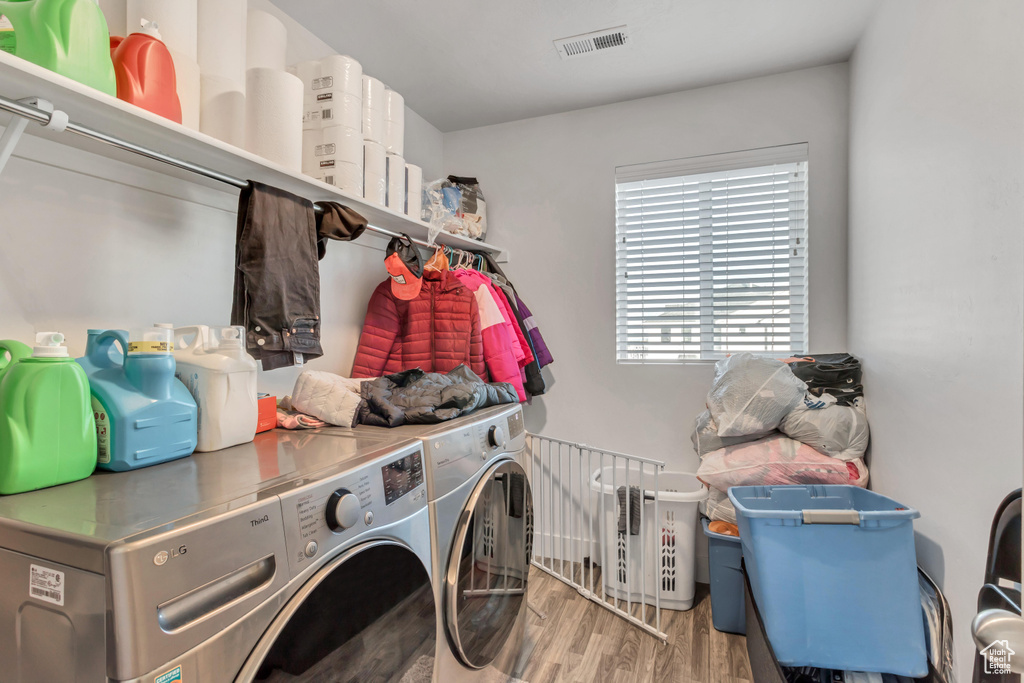 Clothes washing area featuring washing machine and clothes dryer and hardwood / wood-style floors