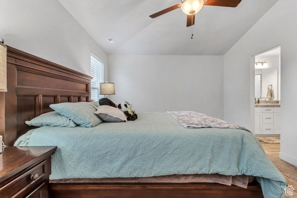 Bedroom featuring vaulted ceiling, light carpet, ensuite bath, and ceiling fan