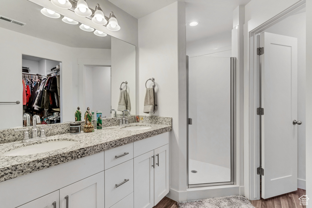 Bathroom with an enclosed shower, hardwood / wood-style flooring, dual sinks, and vanity with extensive cabinet space