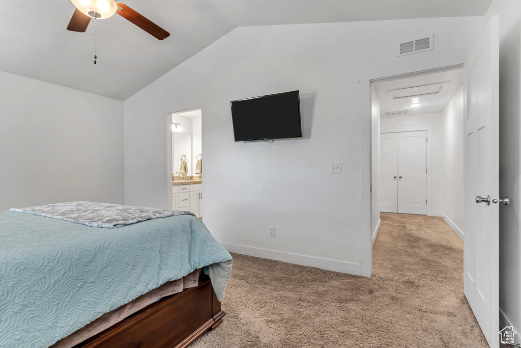Bedroom with connected bathroom, light carpet, ceiling fan, and vaulted ceiling