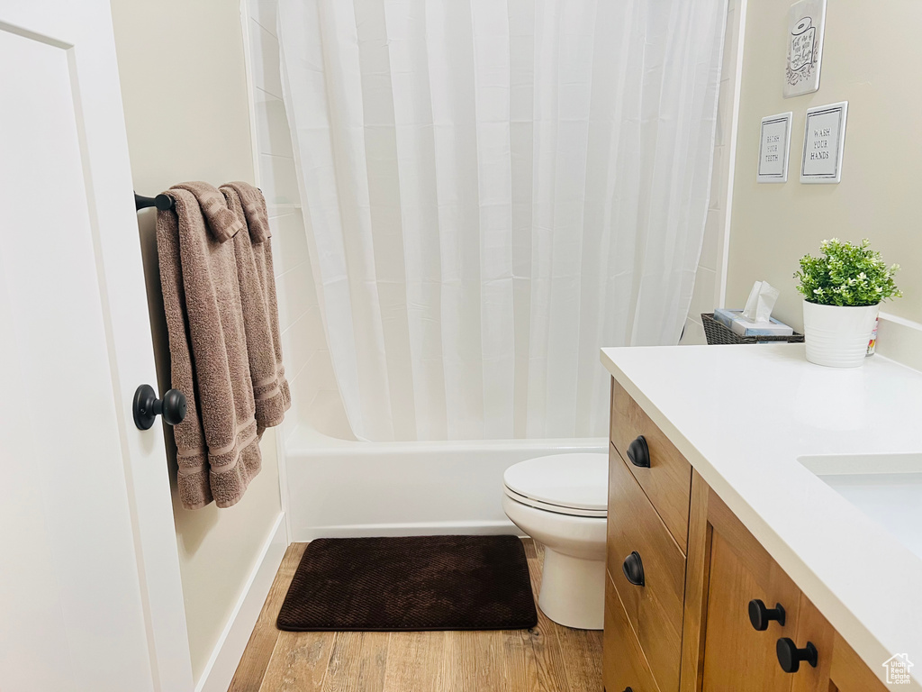 Full bathroom featuring wood-type flooring, toilet, vanity, and shower / bathtub combination with curtain