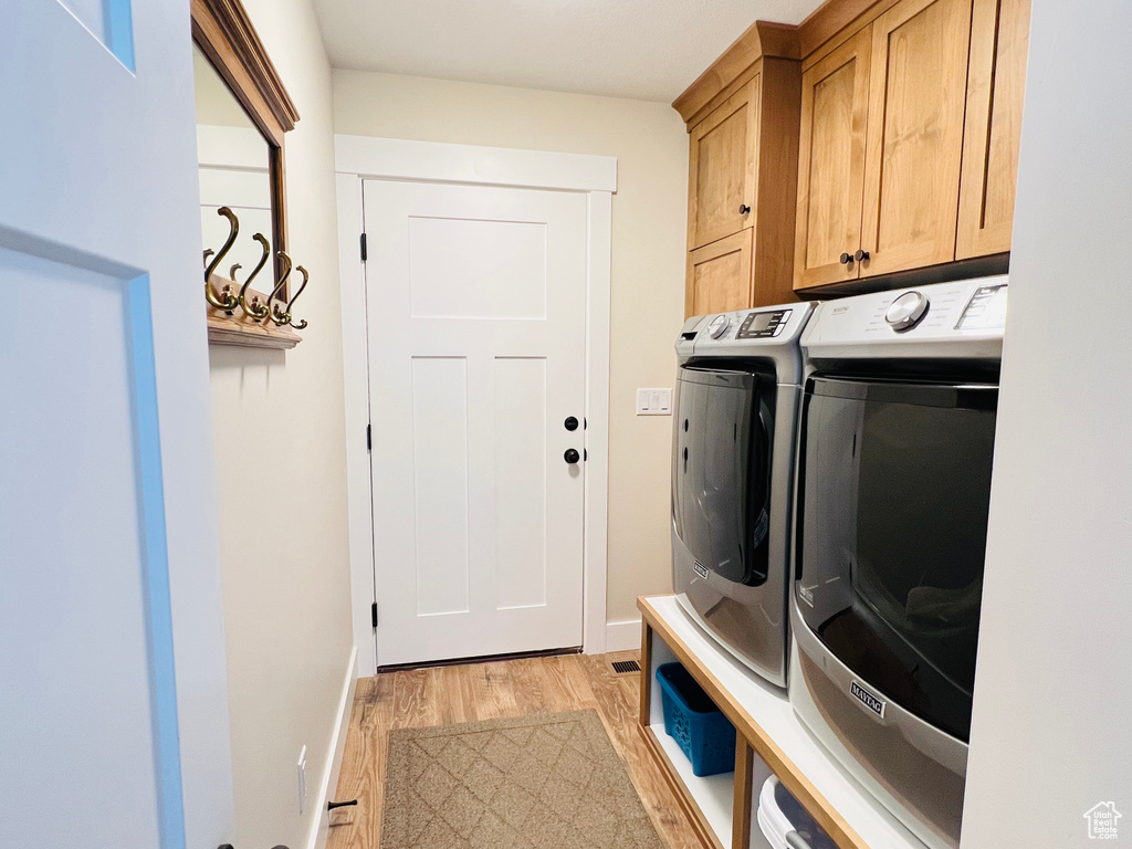 Washroom with cabinets, light hardwood / wood-style flooring, and separate washer and dryer