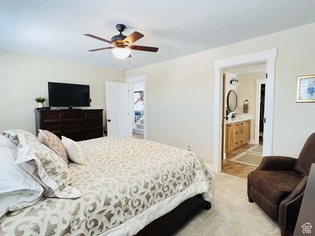 Bedroom with ensuite bathroom, light wood-type flooring, and ceiling fan