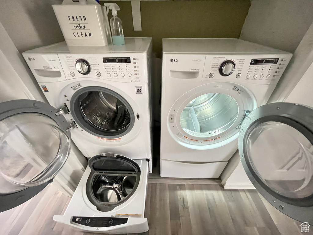 Clothes washing area with dark hardwood / wood-style flooring and washer and clothes dryer