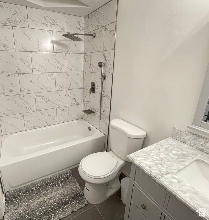 Full bathroom with vanity, toilet, tile flooring, and tiled shower / bath