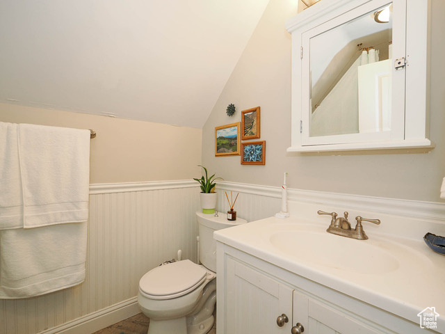 Bathroom with vanity, toilet, and lofted ceiling