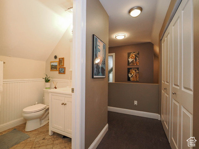 Bathroom with vanity, toilet, vaulted ceiling, and tile flooring