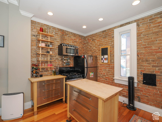 Office area featuring brick wall, ornamental molding, and light wood-type flooring