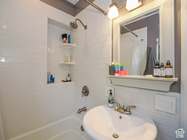 Bathroom with tile walls, shower / tub combo, and sink