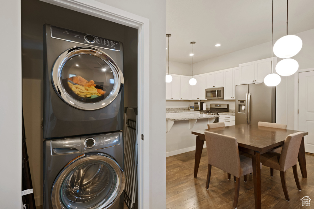 Laundry area with dark hardwood / wood-style floors and stacked washer and clothes dryer