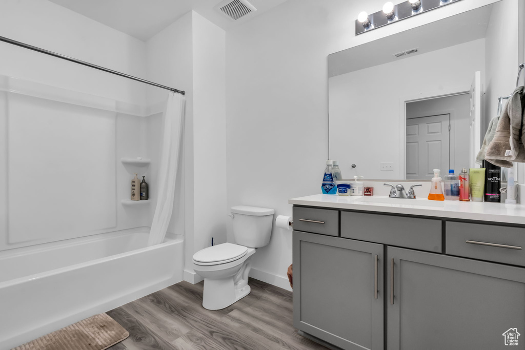 Full bathroom featuring shower / bath combo, hardwood / wood-style flooring, toilet, and vanity