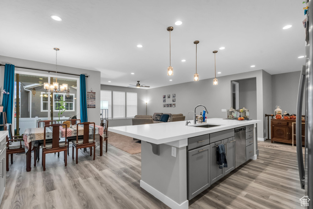 Kitchen with a kitchen island with sink, sink, ceiling fan with notable chandelier, light hardwood / wood-style flooring, and gray cabinets